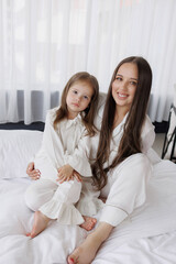 Mother and daughter share a cozy moment in matching pajamas on a Sunday morning