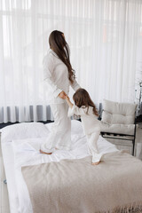 Joyful moment of a mother and daughter playing on a bed in a bright, cozy room