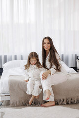 Mother and daughter in matching pajamas enjoying time together in a cozy bedroom