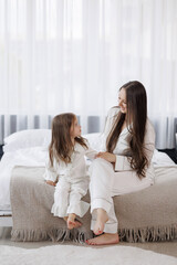 Mother and daughter sharing a joyful moment at home during morning in cozy pajamas