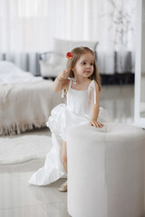 Young girl in white dress playing with flower in bright sunny room