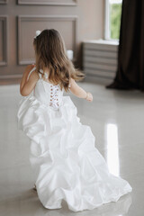 Little girl twirls in a beautiful white dress at a celebration in an elegant indoor venue