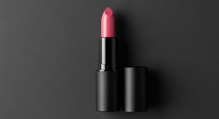 A vibrant pink lipstick with its cap off rests on a dark, textured surface, exuding elegance