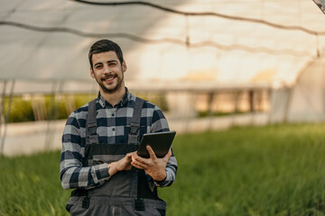 Farmer using digital tablet in greenhouse: monitoring and managing crops with technology