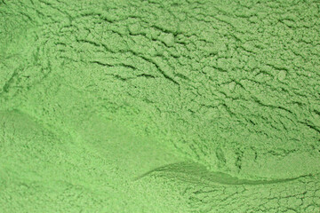 Green powder textured background. Concept of nutritional supplement, dieting, detox, preventive healthcare and healthy lifestyle.	