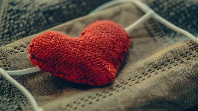 A small, handmade red heart-shaped gift box tied with string and ribbon, containing a sweet treat.