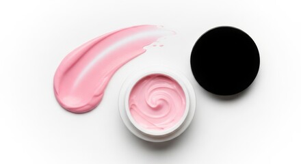 A swirl of pink cosmetic cream next to an open jar and a black lid, isolated on a white background