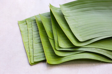 Stacked banana leaves on a white background, commonly used in traditional cooking.