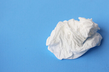 Used crumpled tissues scattered on a blue surface.