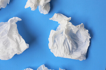 Used crumpled tissues scattered on a blue surface.