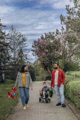 Family with two boys riding bicycles and parents walking nearby in a park. Outdoor fun, bonding,...