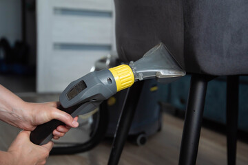 Washing and cleaning a gray chair with fabric upholstery using a washing vacuum cleaner and...