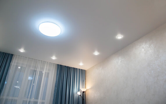 Modern stylish ceiling with diode chandelier and spotlights in the room and turquoise curtains. Copy space for text