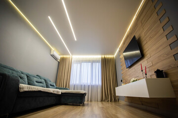 Modern interior in the living room with wooden laminate flooring, wall-hung cabinets and LCD TV. Stretch diode ceiling around the perimeter. Copy space for text, conditioner