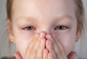 Caucasian girl aged 8 with sad painful look looks at camera, close-up, portrait. Disease concept