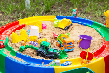 Modern round colorful children's sandbox with toys and molds, close-up
