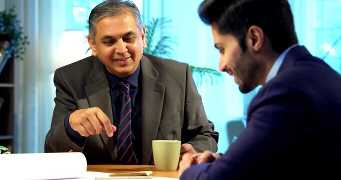 Indian businessmen shaking hands after finalizing plan in modern office, Asian young designers or planners celebrating successful agreement, teamwork collaboration, and corporate partnership