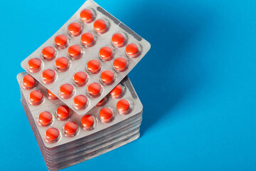Stack of red pills on blue background. Concept of treatment with antibiotics tetracyclines in...
