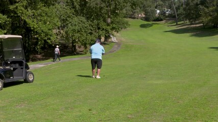 A golf player walks towards the ball on the course.