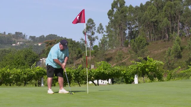 After making a few test strokes, the golfer gently taps the ball into the cup at the flagpost.