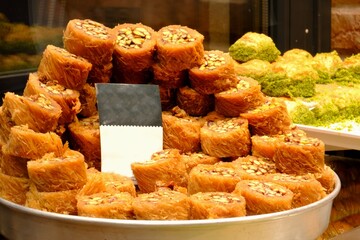 Close-up view of kadayıf desserts with pistachios sold on a tray in a dessert shop. Traditional Turkish desserts. Sherbet desserts. Kadayıf wrap with pistachios. Turkish delight.