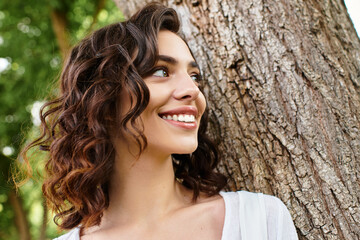 Young woman enjoying a sunny day in a vibrant park with lush greenery and a smile