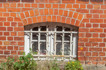 Kellerfenster mit verzierten Fenstergitter an einer Backsteinmauer, Deutschland