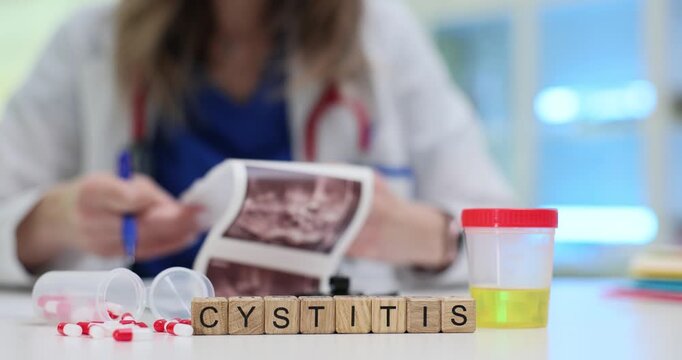 Light shines on table focusing on word Cystitis made from wooden blocks. Female medical worker holds ultrasound image researching bladder problem