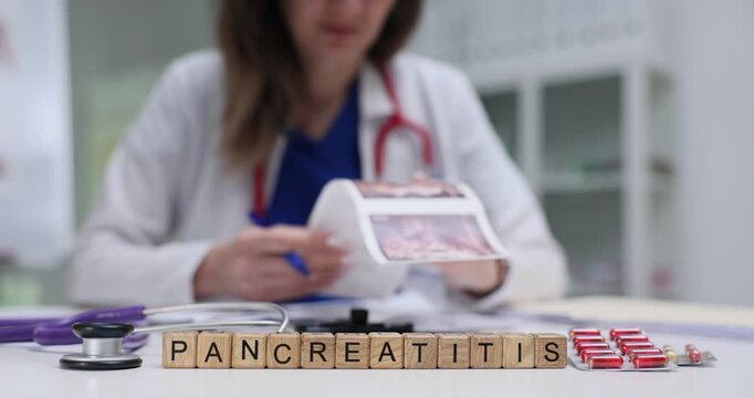 Cubes spell Pancreatitis placed on table near stethoscope and scan image. Woman medical studies ultrasound creating diagnosis for pancreas problem