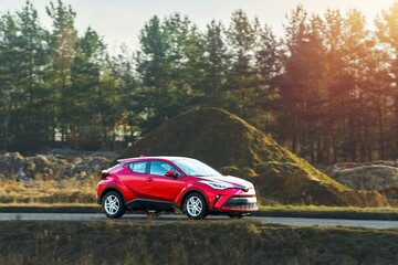 Red SUV driving on an open road in summer