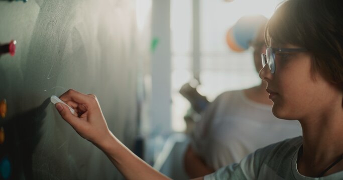 Smart Pupil Showcasing Math Knowledge: Close Up Shot of Elementary School Boy Solving Mathematical Problems Writing on the Chalkboard in Front of Classroom. Female Teacher Checking Correct Answers. - Powered by Adobe