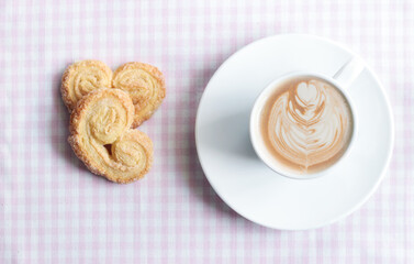 Coffee with Latte Art and Palmier Cookies on Rustic Table

