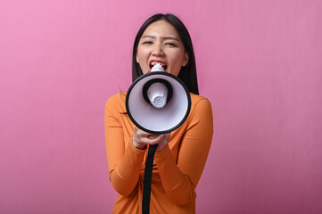 Asian woman with long black hair wearing an orange dress holding a megaphone directly facing the...