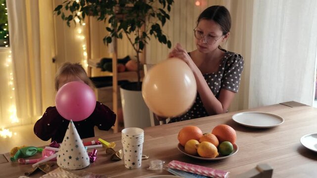 Family Fun Children Joyfully Blowing Up Balloons. Kids inflating balloons, prepare for birthday party. 3,6, 14 years old siblings racing blowing balloon, decorate the room. Bonding time together. Joy