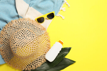 Flat lay composition with beach towel and other summer accessories on yellow background. Space for...