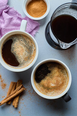 Top view of a cup of coffee and pot, cinnamon on grey background