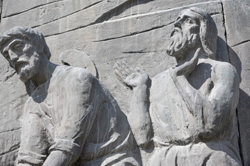 Stone element with figures of people monument The chronicle of Georgia against the blue sky, Tbilisi, Georgia