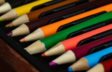 Close-up of multi colored pencils or wooden crayons to each other arranged in a neat row in wooden...