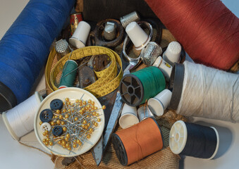 Sewing needles stuck in a green miniature spools thread Steel scissors, Spools of thread of various...
