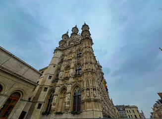  Gothic architecture of Leuven town hall under cloudy sky with christmas preparations