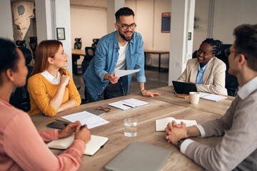 Team Collaborating Energetically During a Professional Business Meeting Around a Wooden Desk
