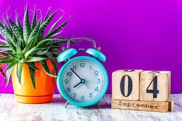 Wooden calendar with the date September 4.Monthly calendar for planning and management concept with alarm clock on wooden background