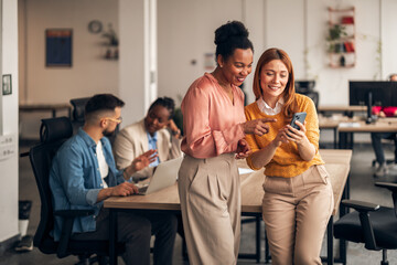 Colleagues Sharing a Moment While Viewing a Smartphone in a Modern Office