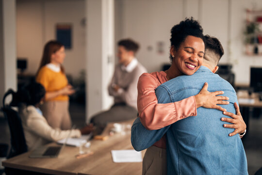 Happy Business Colleagues Hugging in a Modern Office Environment