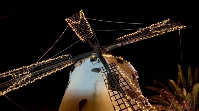 A breathtaking view of a beautifully lit windmill set against the night sky, showcasing its intricate and unique design
