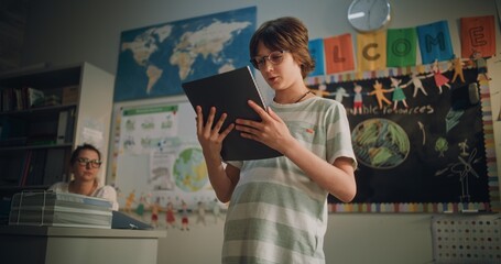 Renewable Energy Lesson: Elementary School Boy Holding Notebook Speaking, Giving Presentation on...