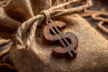 Wooden dollar sign charm on a burlap bag with a rustic twine bow