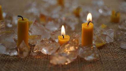 Yellow candles burning amongst clear crystals on burlap image
