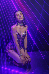 sexy woman in dark black room night club laser party neon blue color light studio shooting photo session beauty face makeup eyes lips wet hair skin. Girl fashion model posing pink glisten shiny dress
