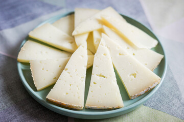 Sliced cured cheese arranged on a green ceramic plate
